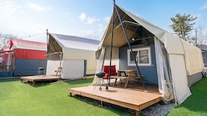 Un camping con dos tiendas de campaña, cada una con una plataforma de madera y una mesa.