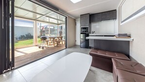 A modern kitchen with a built-in oven, a dining area with a bench, and a sliding glass door leading to a patio. - Gapyeong Ilekaempingjang (Gapyeong)