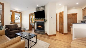 A modern living room with a fireplace, wooden flooring, and a flat-screen TV mounted above it. - Remodeled Granby Ranch Condo - 20 miles to RMNP w/ Hot Tub & Firepit (Granby)