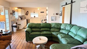 Een gezellige woonkamer met een groene modulaire bank, een ronde salontafel en een houten vloer.