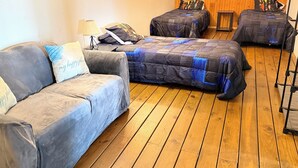 Een kamer met twee bedden, een bank en een houten vloer.