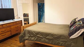Een slaapkamer met een bed, een houten dressoir en een televisie.