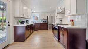 Une cuisine moderne avec des meubles de couleur blanche et de couleur bois foncé, des appareils en acier inoxydable et un plancher en bois.