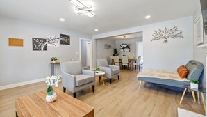 Un salon moderne avec un canapé, des fauteuils, une table basse et des œuvres d’art accrochées aux murs.