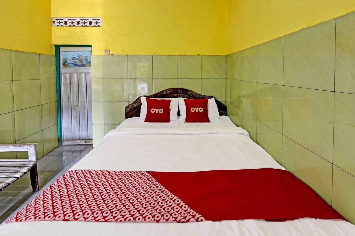 Una habitación de hotel con una cama, un banco y una puerta.