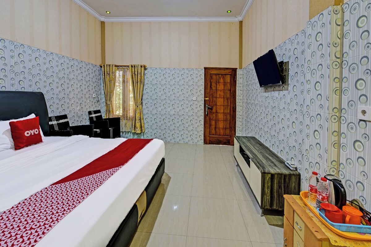 Ein Hotelzimmer mit einem Bett, einer Holzbank, einem an der Wand montierten Fernseher und einem kleinen Tisch mit Toilettenartikeln.