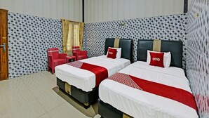 A hotel room with two beds, a small seating area, and patterned wallpaper. - Spot On 91376 Hotel Bintang Flores (Cilacap)