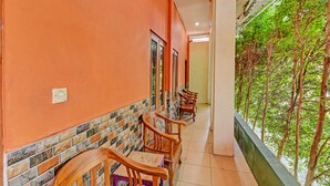 A corridor with wooden chairs and a tiled wall. - Spot On 91376 Hotel Bintang Flores (Cilacap)