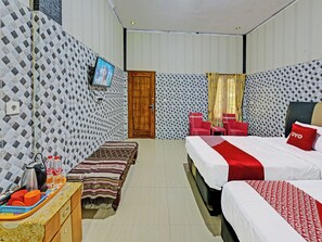 Ein Hotelzimmer mit Bett, einer Sitzbank, einem Fernseher, einer Holztür und einem Fenster mit Vorhängen.