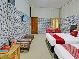 Habitación de hotel con cama, un banco, un televisor y una pequeña mesa con hervidor y tazas.