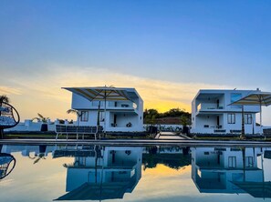 A modern hotel with two-story buildings, a swimming pool, and outdoor seating.