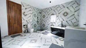A bathroom with a toilet, bidet, and a bathtub with a black faucet.