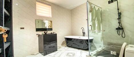 A modern bathroom with a marble floor, a freestanding bathtub, a glass-enclosed shower, and a toilet.
