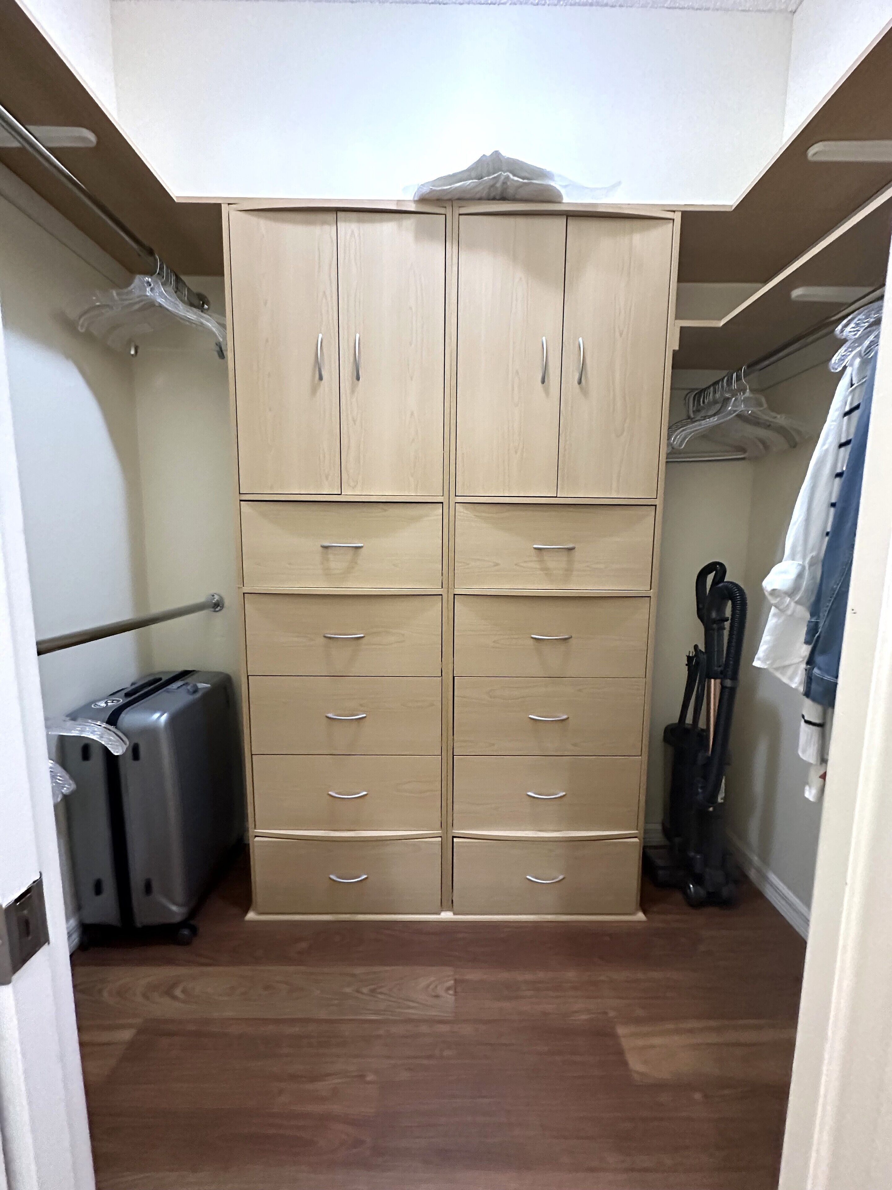A walk-in closet with a mirrored wardrobe, multiple drawers, and hanging space.