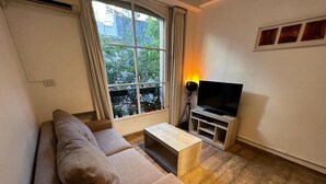 A living room with a sofa, a coffee table, a TV stand, and a window with curtains. - Beautiful apartment with excellent location (Buenos Aires)