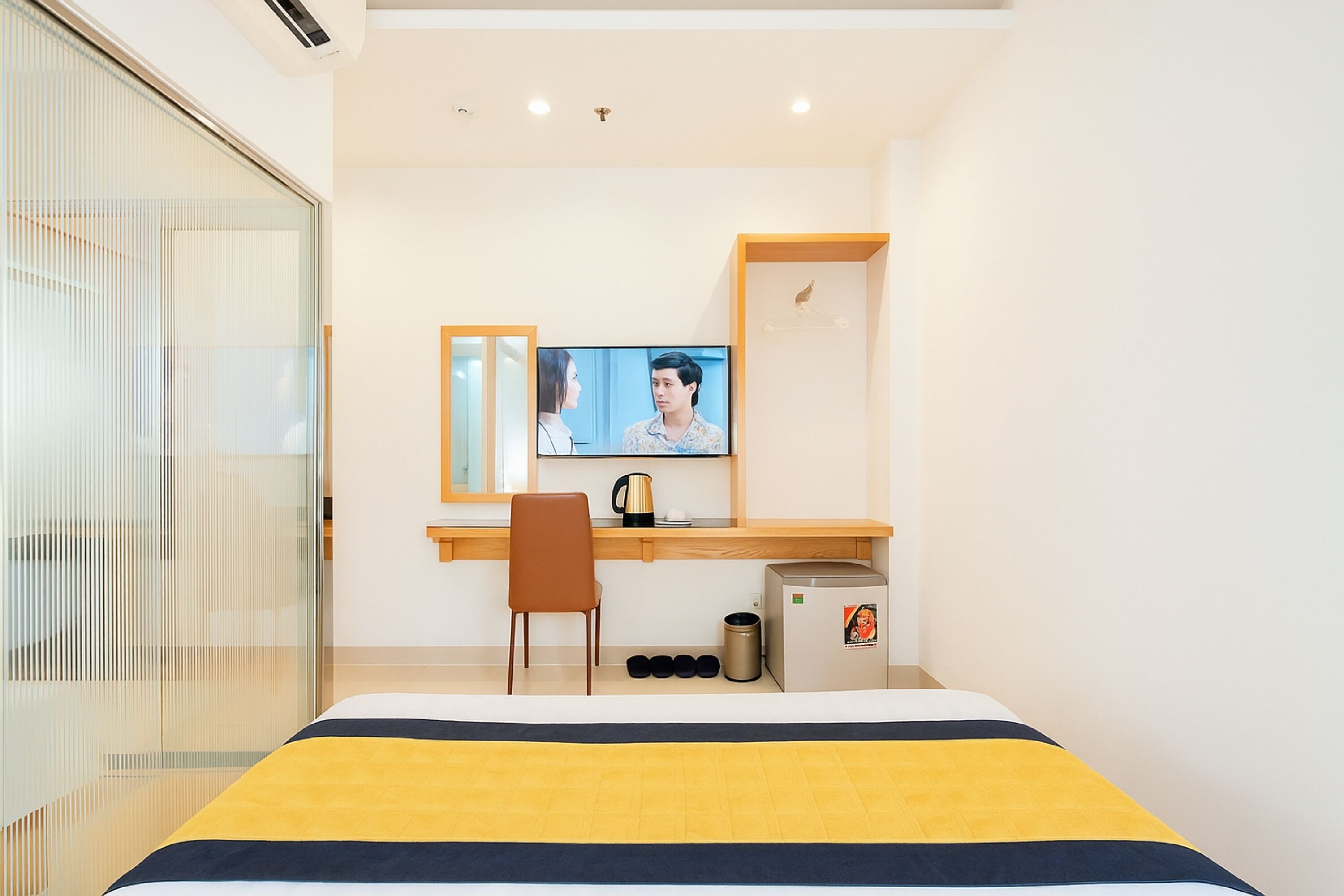 A modern hotel room with a bed, a desk, a television, and a coffee maker.