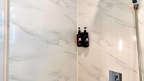 A modern bathroom with a marble wall, a handheld showerhead, and two bottles of shampoo. - S79 Son Mi 839 Le Hong Phong Street (Ho Chi Minh City)