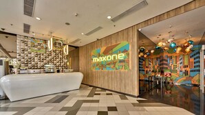 A modern hotel lobby with a reception desk, a colorful mural, and a checkered floor. - MaxOneHotels Premier Melawai (Jakarta)