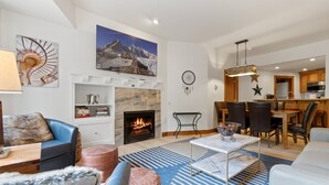 Ein modernes Wohnzimmer mit Kamin, einem Essbereich und einer Küche im Hintergrund.
