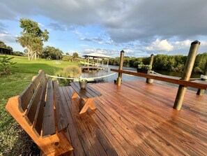 A wooden deck with picnic tables and a rope barrier overlooking a body of water.