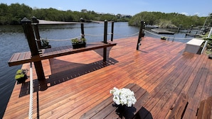 Eine Holzterrasse mit Seilgeländer, Topfpflanzen und einer Sitzbank.