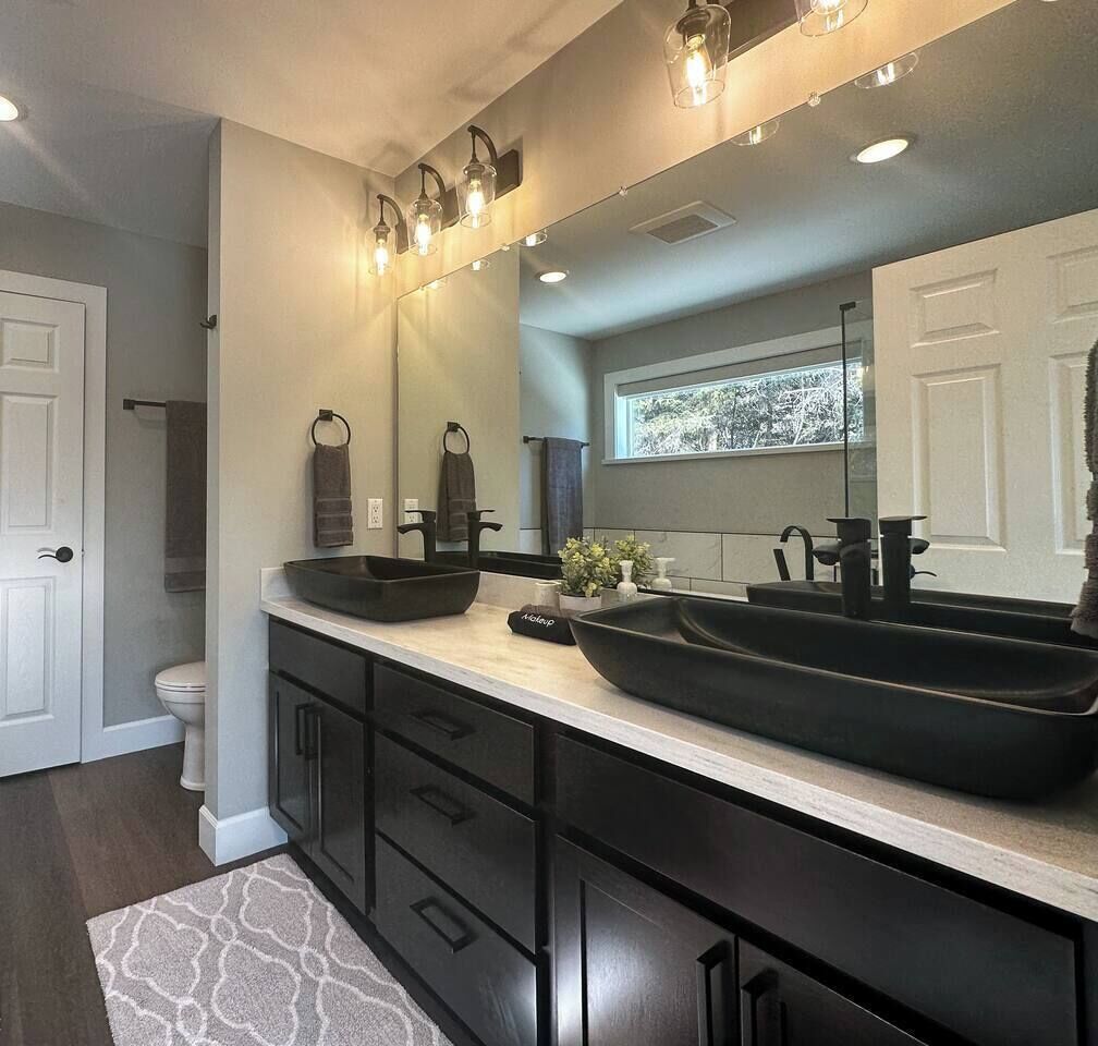 A modern bathroom with a double sink, dark cabinetry, and a large mirror.