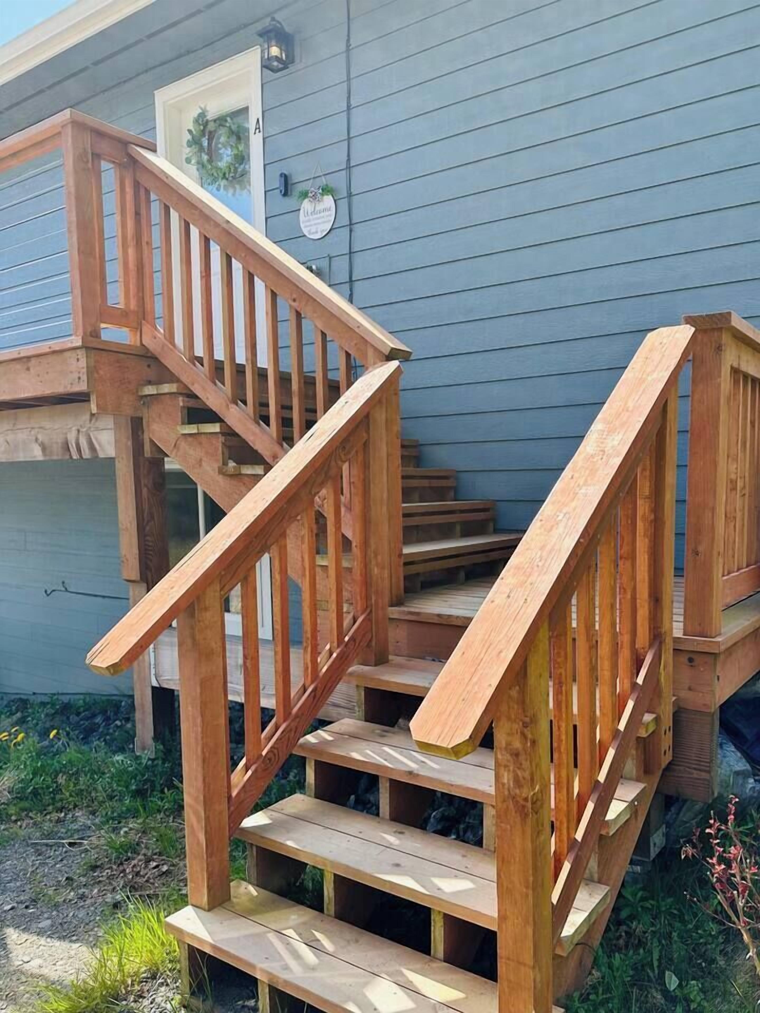 Una escalera de madera que lleva a una terraza con una casa al fondo.