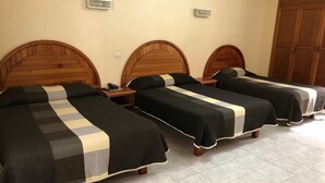Une chambre d’hôtel avec trois têtes de lit en bois, un sol carrelé et une armoire.