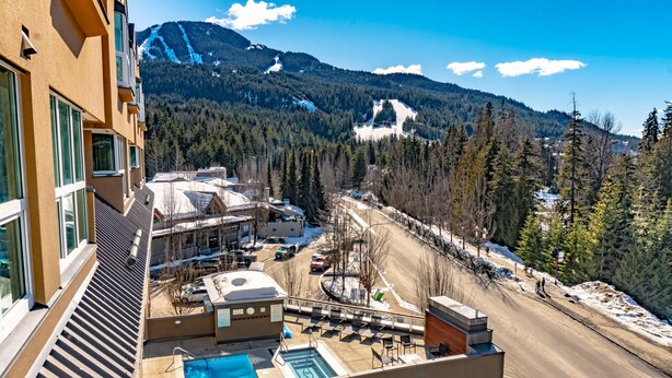 A hotel with a pool, ski slope view, and a road with snow. - Le Chamois 211 - Ski in Ski out, Common Pool, Hot Tub & Gym (Whistler)