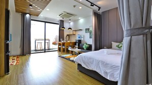 Une chambre d’hôtel moderne dotée d’un grand lit, d’un coin repas et donnant sur l’extérieur grâce à une porte vitrée.