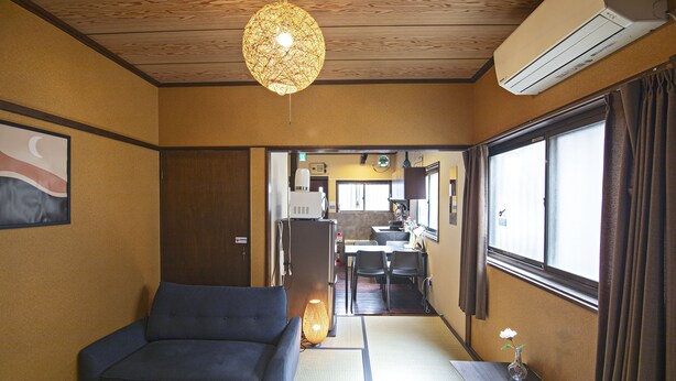 Perinteinen japanilaistyylinen huone, jossa on tatamimatto, matala pöytä maljakolla ja sohva.