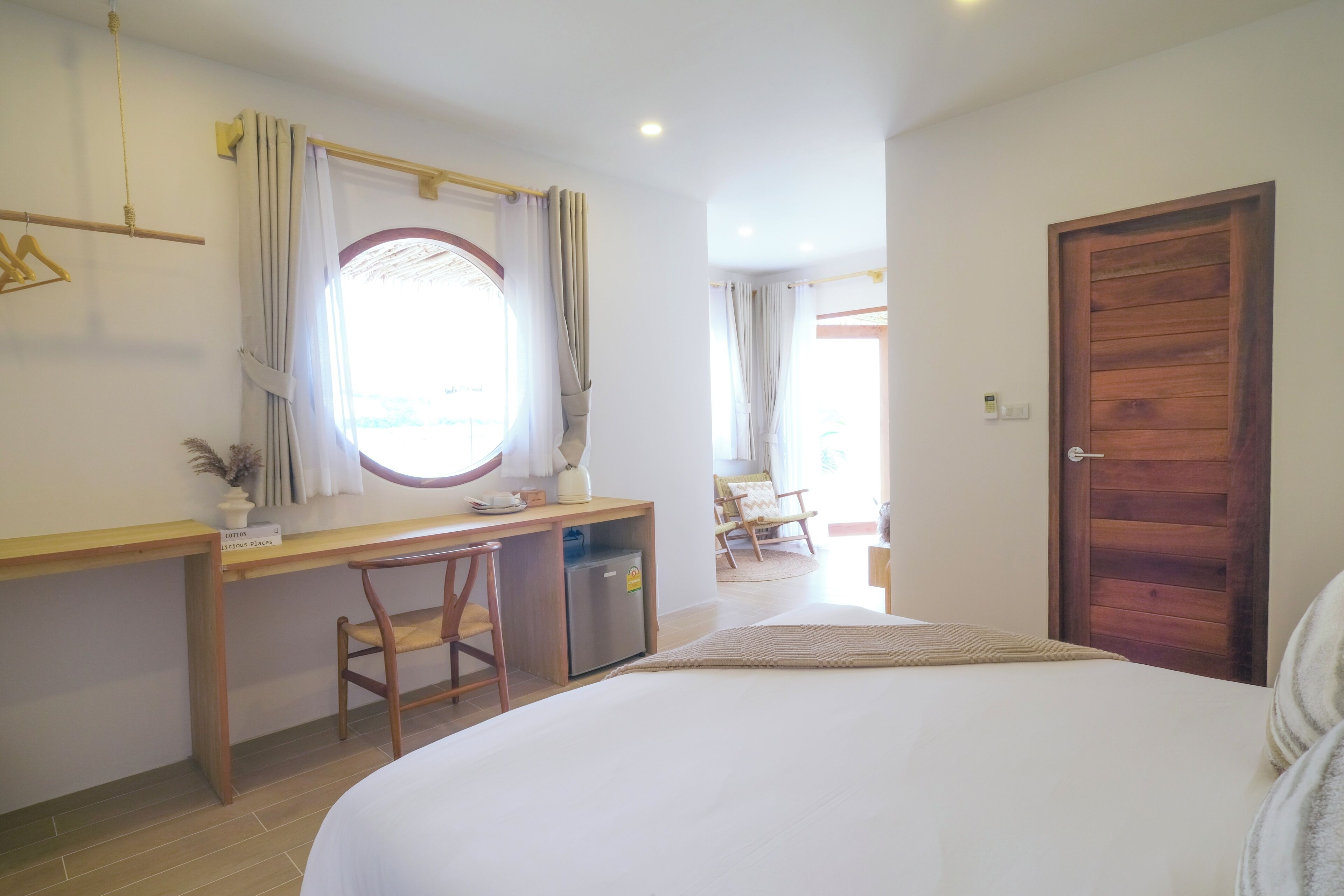Un dormitorio con cama, escritorio, silla, refrigerador pequeño y puerta de madera.