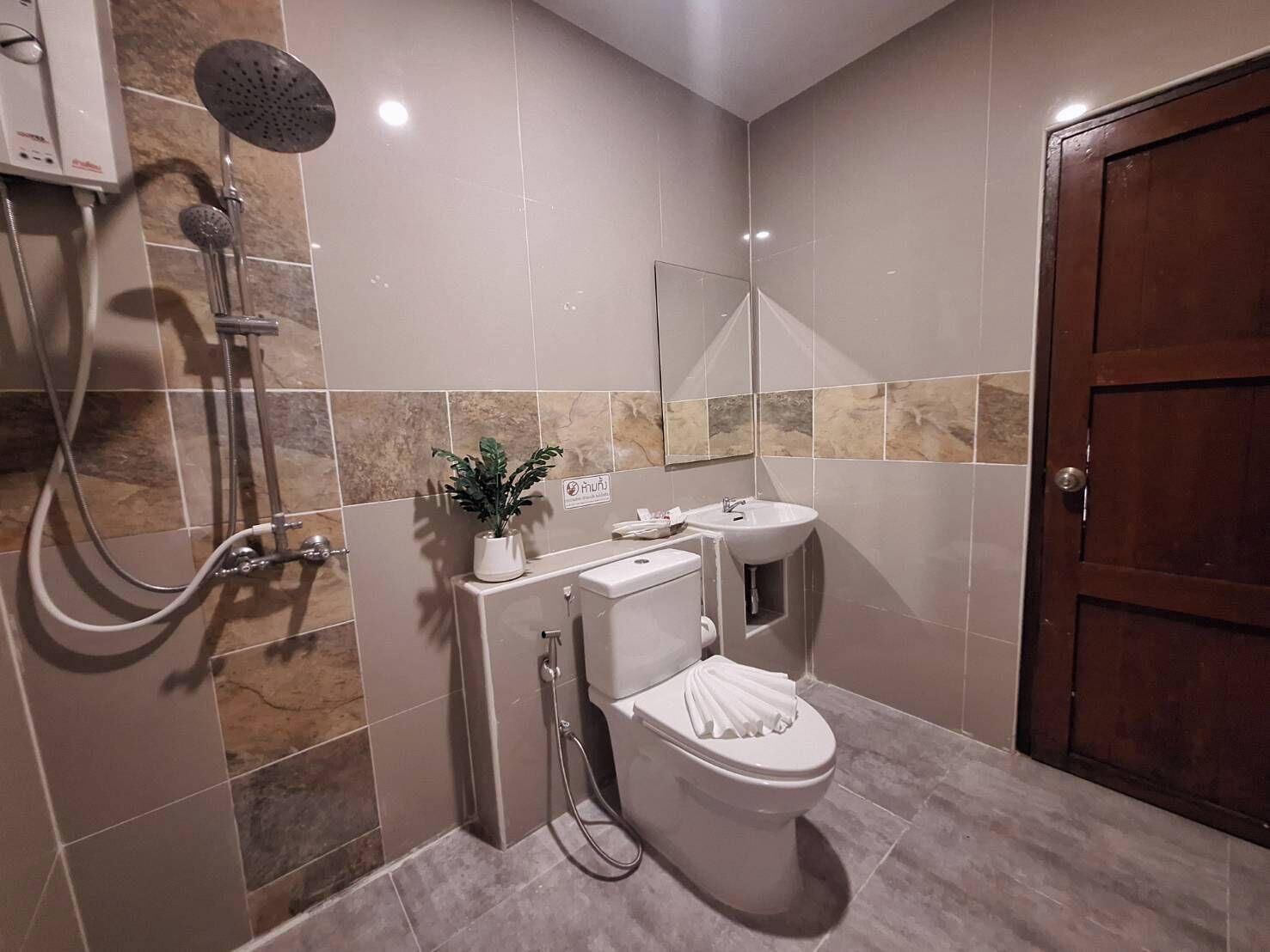 Ein Badezimmer mit Dusche, Toilette, Waschbecken und einer Zimmerpflanze.
