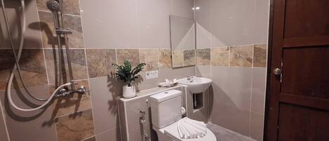 Ein Badezimmer mit Dusche, Toilette, Waschbecken und einer Zimmerpflanze.