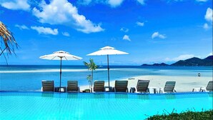 A poolside area with lounge chairs and umbrellas, overlooking a beach and ocean. - Smile Samui Chaweng Beach Front Resort (Koh Samui)