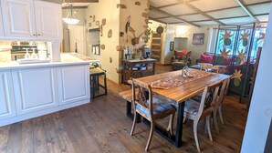 A rustic kitchen with wooden flooring, a central island, and a dining area with a long wooden table and chairs. - Lakefront tranquil chalet with spa near all outdoor activities (Val-Morin)