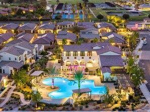 A residential area with multiple houses, a swimming pool, and a well-lit driveway.