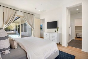 A bedroom with a bed, a dresser, a flat-screen TV, and a sliding glass door leading to a balcony. - PGA West Haven: Hot Tub, BBQ & Casita (La Quinta)