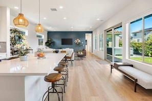 Una cocina moderna con una isla grande, taburetes de bar e iluminación colgante.