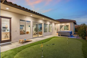 Une maison moderne dotée d’un patio, d’un jacuzzi et d’une pelouse bien entretenue.