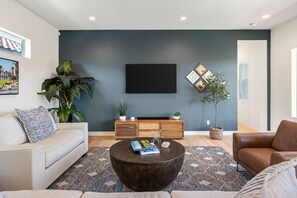 Un salon moderne avec un canapé, une table basse et un téléviseur à écran plat fixé au mur.