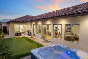 Una casa moderna con un patio, un jacuzzi y un césped bien cuidado.