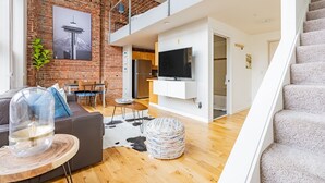 Um apartamento moderno com parede de tijolos, área de jantar, cozinha com televisão e escada.
