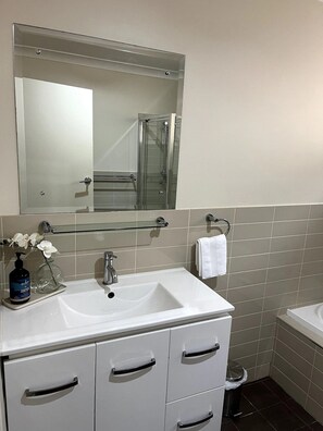 A bathroom with a white sink, a glass shower enclosure, and a mirror above the sink.