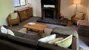 Una sala de estar con chimenea, un sofá, una mesa de centro y una lámpara.