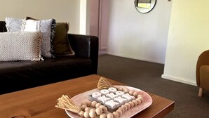 Una mesa de madera con un plato de letras de madera y un arreglo decorativo de ramitas.
