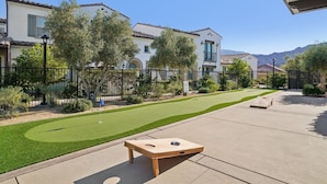 A residential area with a well-maintained lawn, a wooden board game table, and a house with a tiled roof. - Prime PGA West Escape, Pool, BBQ and Patio (La Quinta)