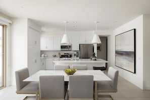 Uma cozinha moderna com armários brancos, uma ilha central e iluminação pendente.