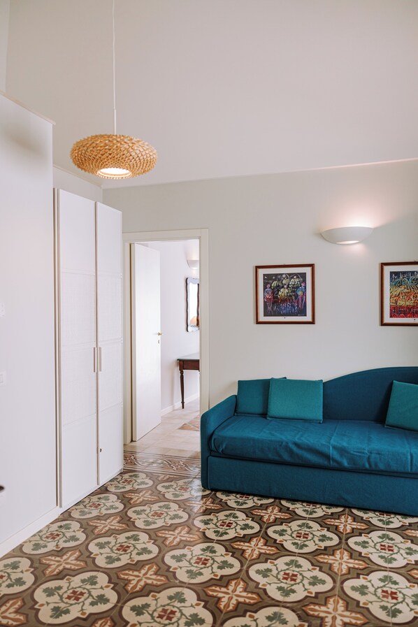 A hallway with patterned flooring, a blue sofa, and a woven light fixture.