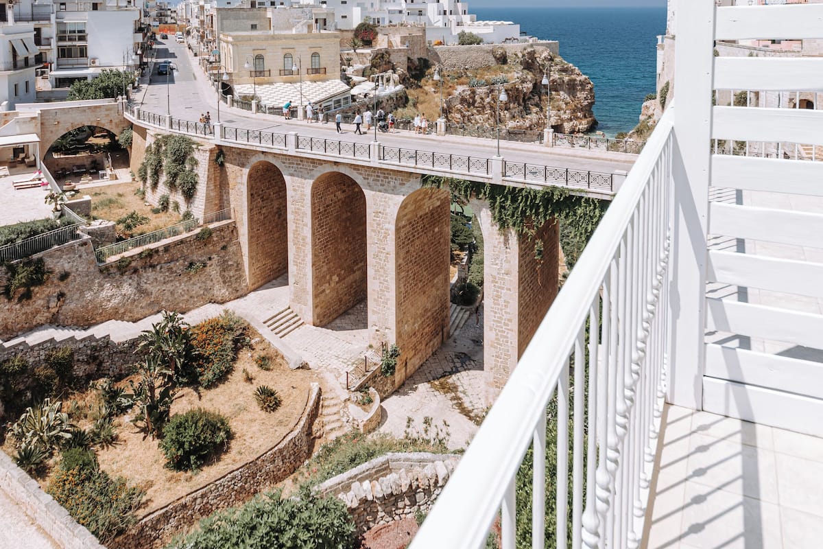 A coastal town with white buildings, a bridge, and a clear blue sky.